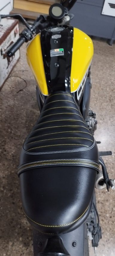 Moto deportiva con asiento negro y detalles amarillos en un entorno interior.