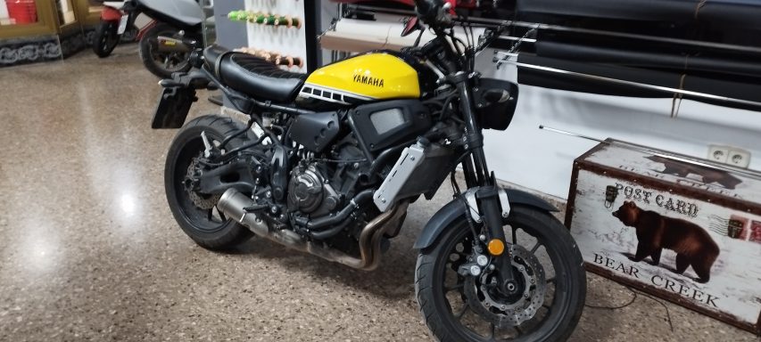 Motocicleta negra y amarilla, modelo moderno, estacionada en un taller.