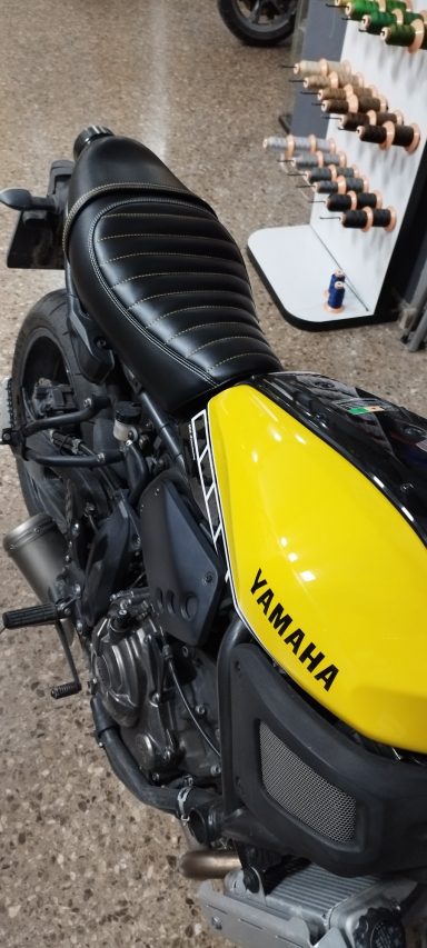Motocicleta Yamaha con asiento negro y tanque amarillo en un entorno interior.