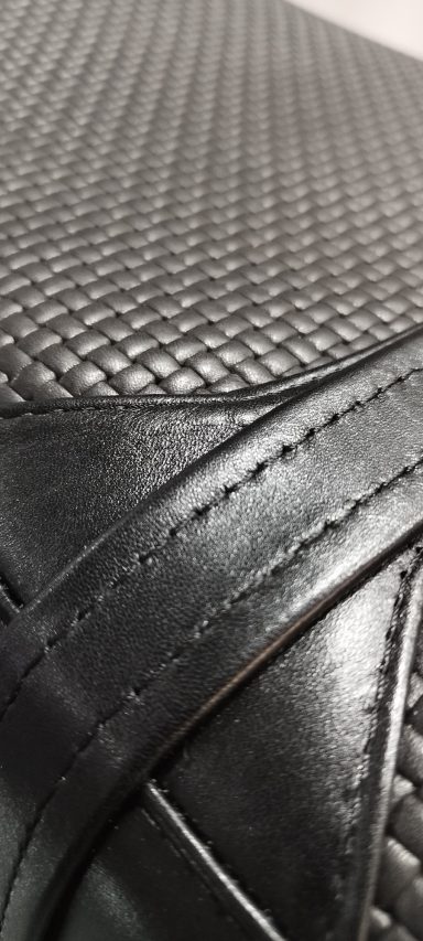 Textura de un material negro con patrón de trenzado y costuras visibles.