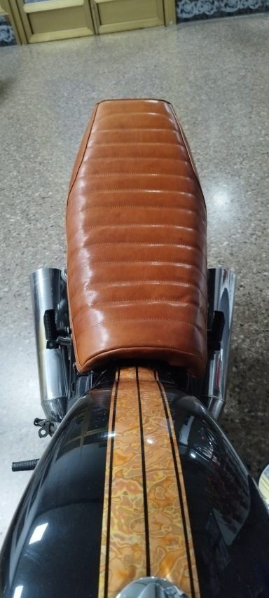 Asiento marrón con costuras en moto, visto desde arriba.