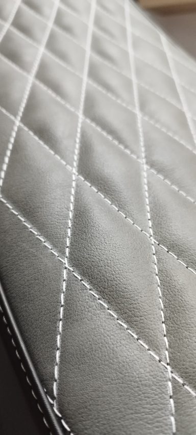 Textura de superficie acolchada en tono gris con costuras en forma de diamante.