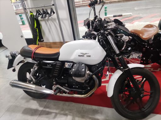 Motocicleta blanca con detalles en marrón, estacionada en un taller.