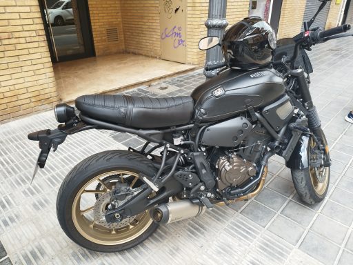 Motocicleta negra con detalles dorados, estacionada en una calle.