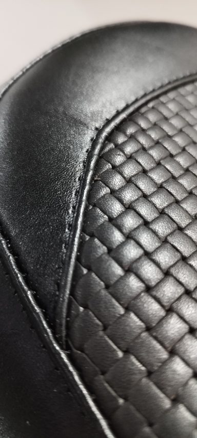 Superficie de cuero negro con patrón de tejido entrelazado.