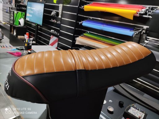Asiento de moto de color marrón y negro con costuras decorativas.