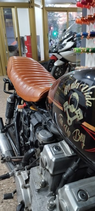 Motocicleta con asiento de cuero marrón y detalles decorativos en el tanque.