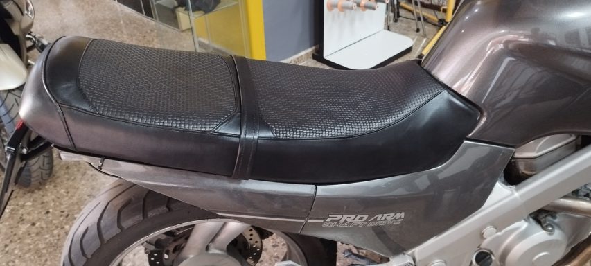 Asiento de motocicleta negro, con textura suave y forma contorneada.